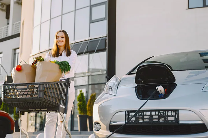 Lady coming back from the shopping while Xova charger charging the her EV