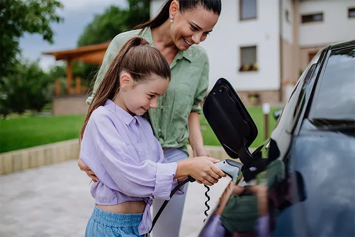 Mother and daughter charging their EV in front of School