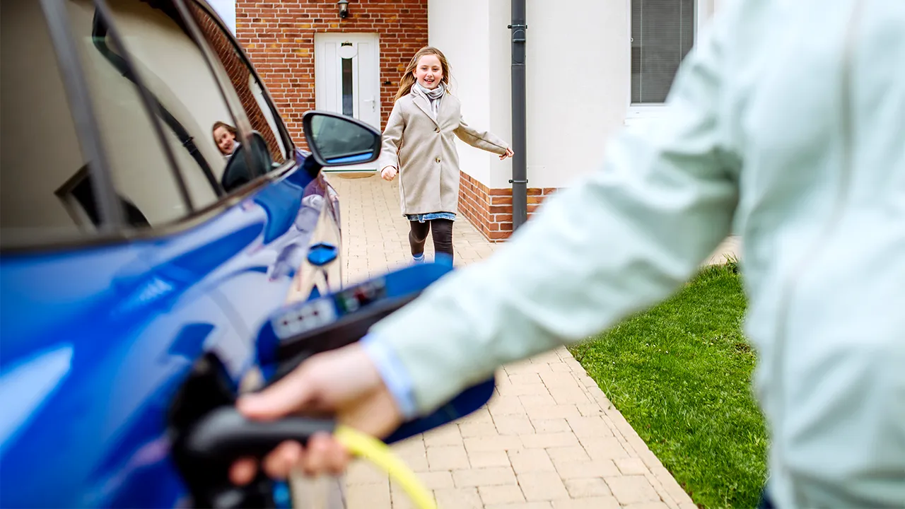 mother charging her EV at her home and her daughter happy running towards to her 